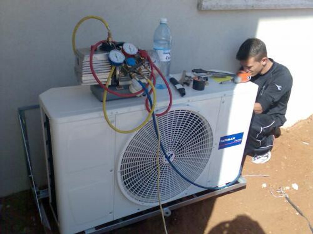 Technician installing Daikin outdoor AC unit with drill, close-up