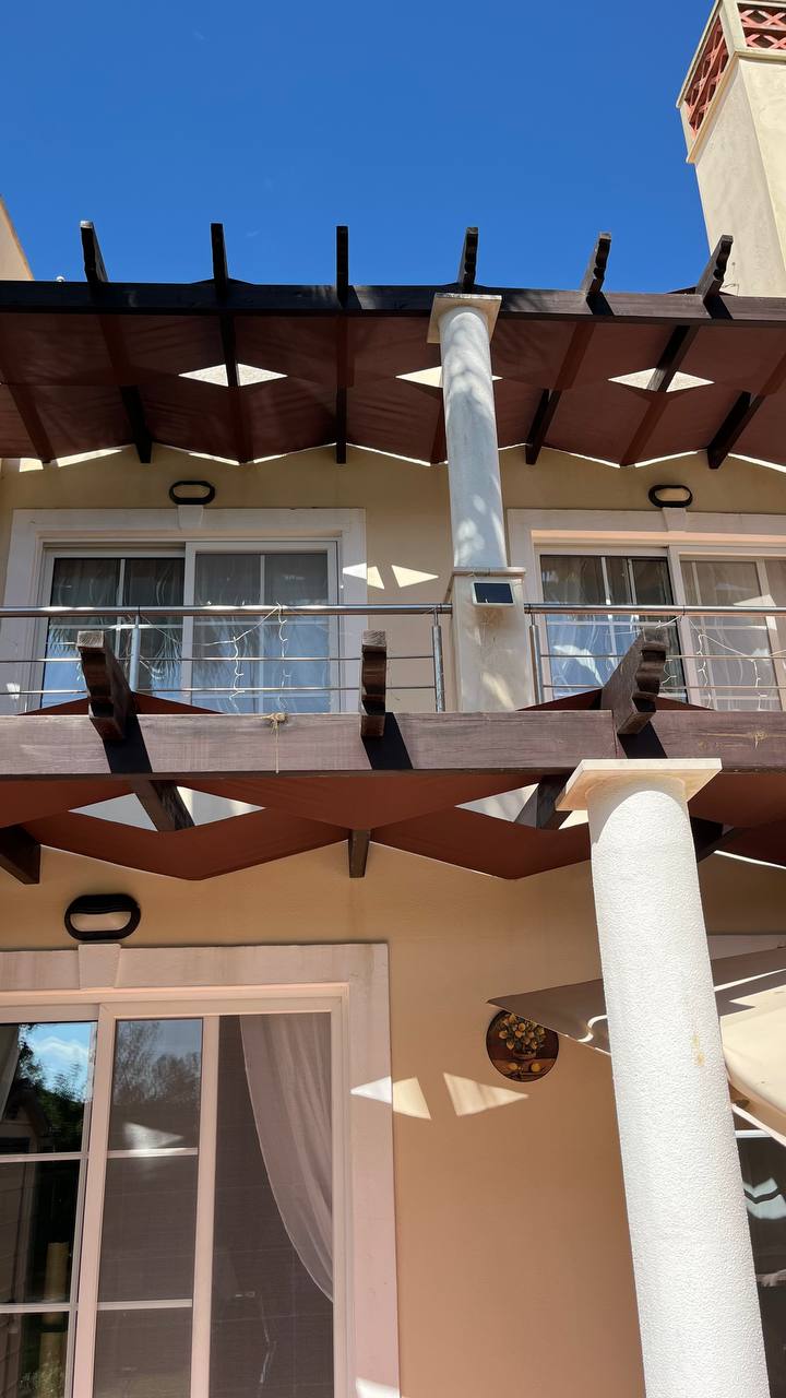 Dark wood pergola shade structure on two-storey building exterior, Algarve
