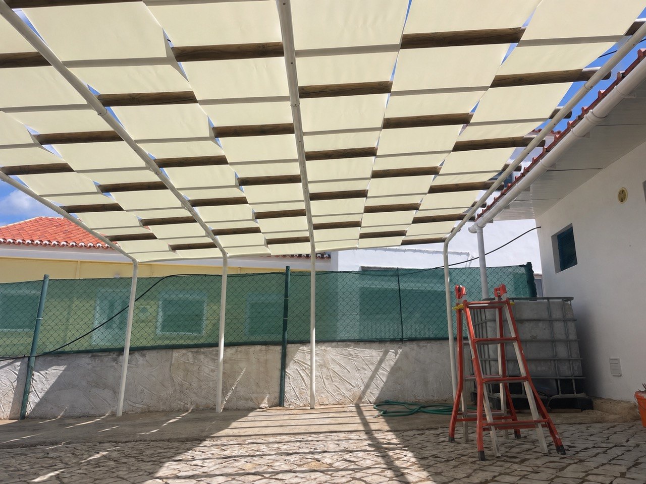 Wide view of pergola with cream fabric shade canopy over terrace, Algarve
