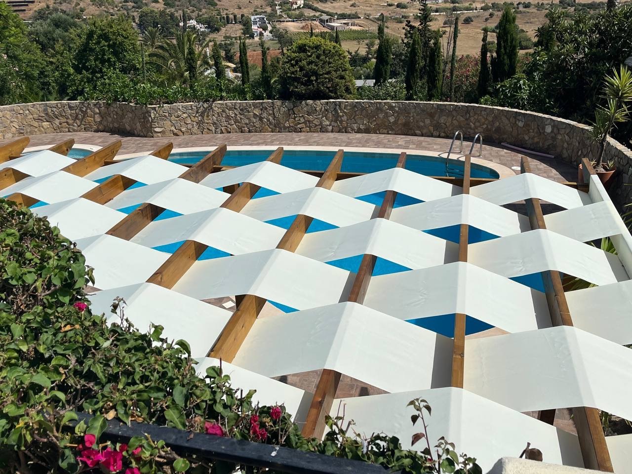 Aerial view of woven fabric pergola shading a round swimming pool, Algarve