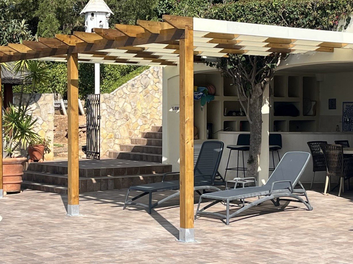 Wooden pergola with diagonal fabric weave shading a poolside lounge terrace, Algarve villa