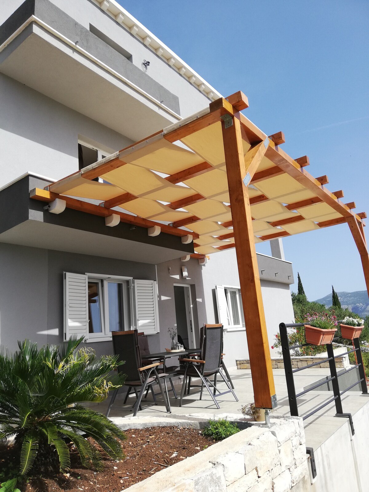 Yellow fabric pergola shade attached to house terrace with outdoor seating, Algarve