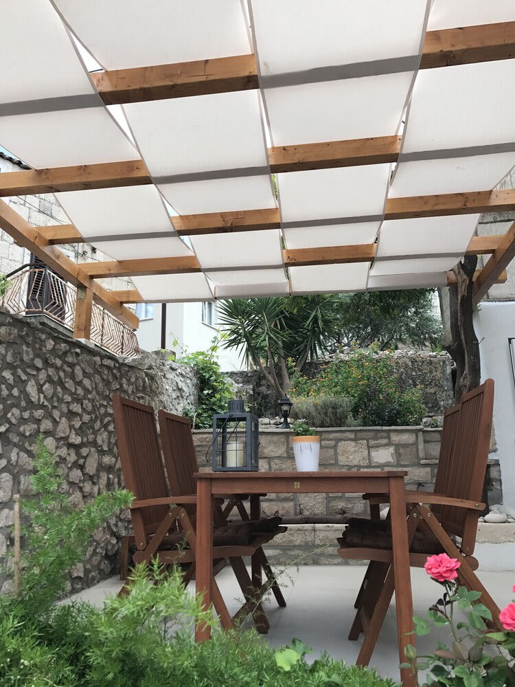 View from below of white fabric shade canopy on wooden pergola, outdoor dining table, Algarve