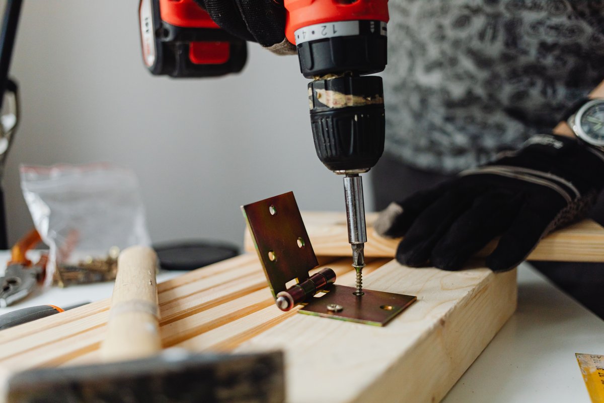 Close-up of hinge repair with power drill on wooden furniture, Algarve