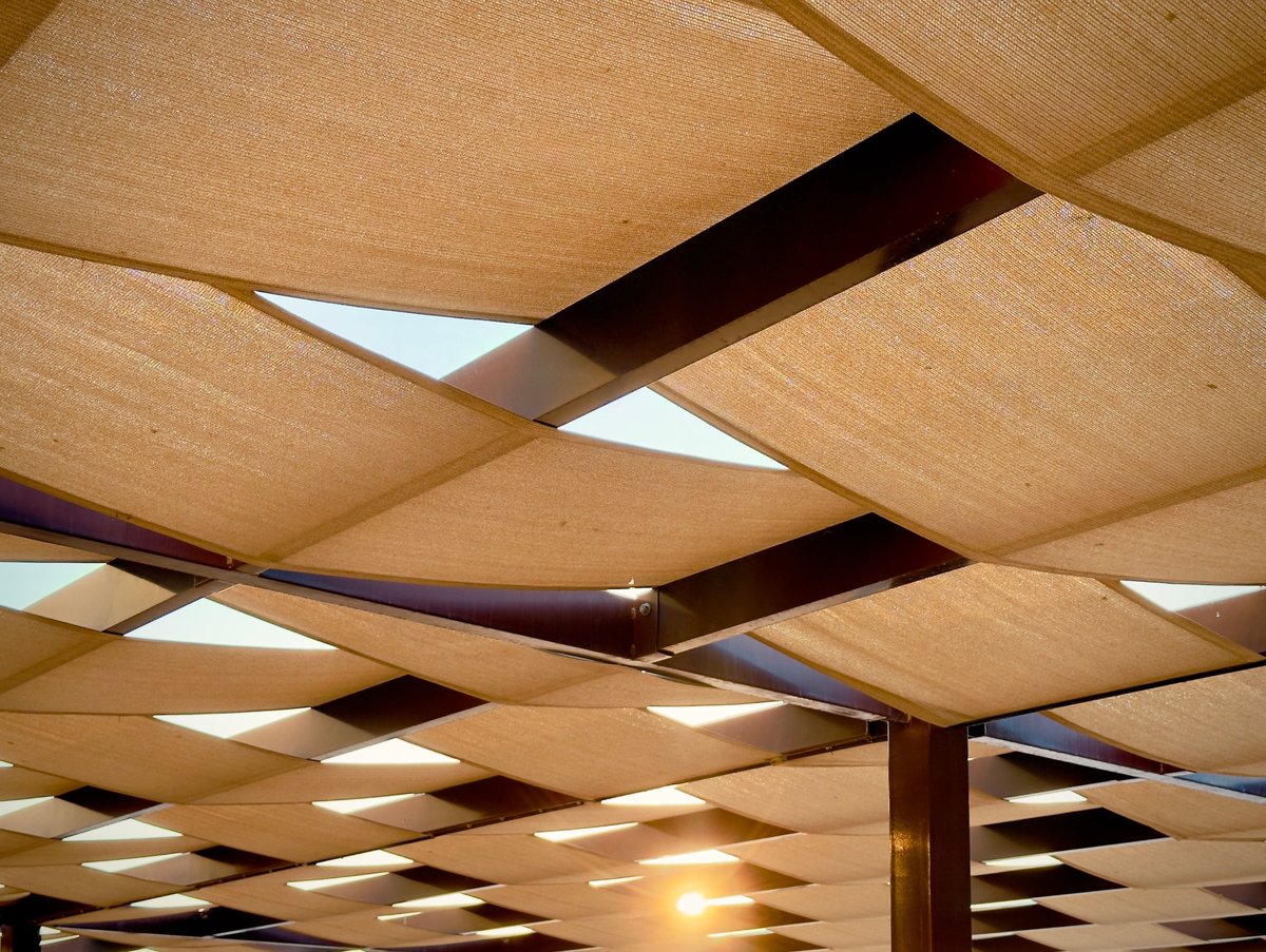 Pergola with woven fabric shade canopy in warm sunlight, Algarve terrace