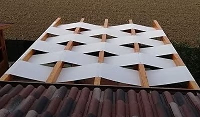 Fabric shade canopy being installed on wooden pergola frame