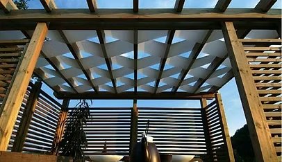Close-up of wooden pergola lattice with woven shade panels, sunset light