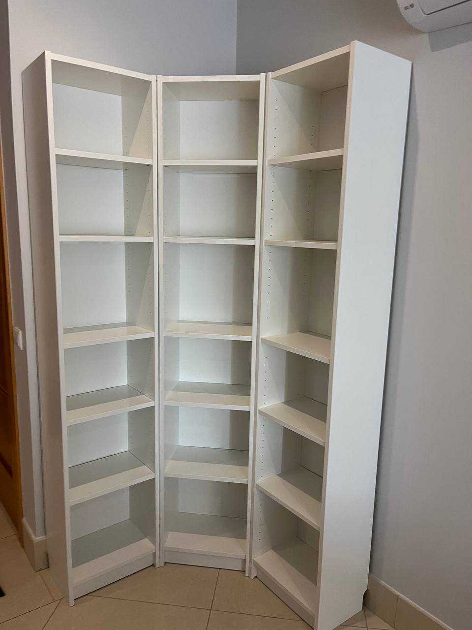 Three white Billy bookshelves assembled in corner layout, Algarve apartment