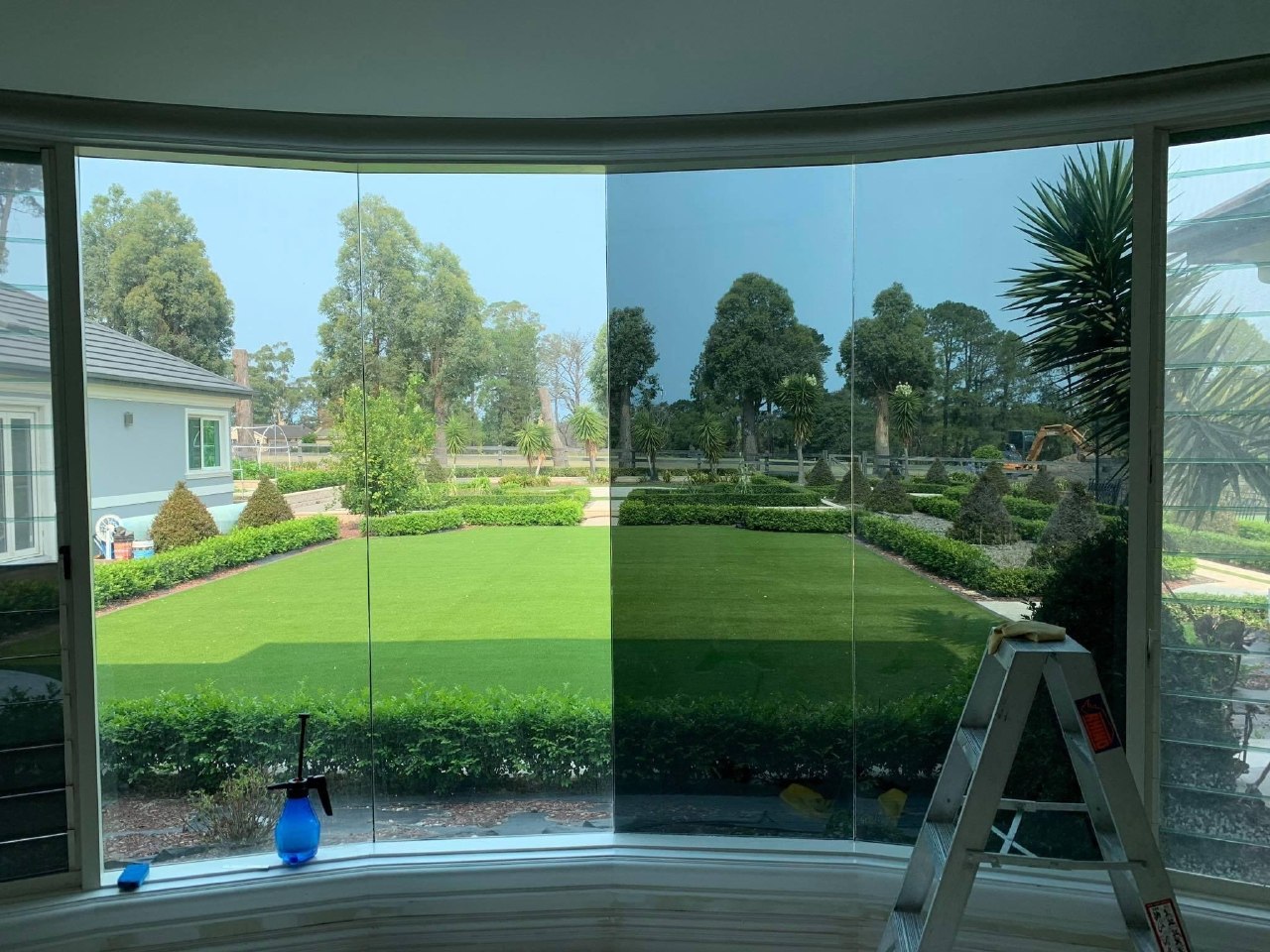 Solar control film being applied to large curved bay windows with garden view, Algarve
