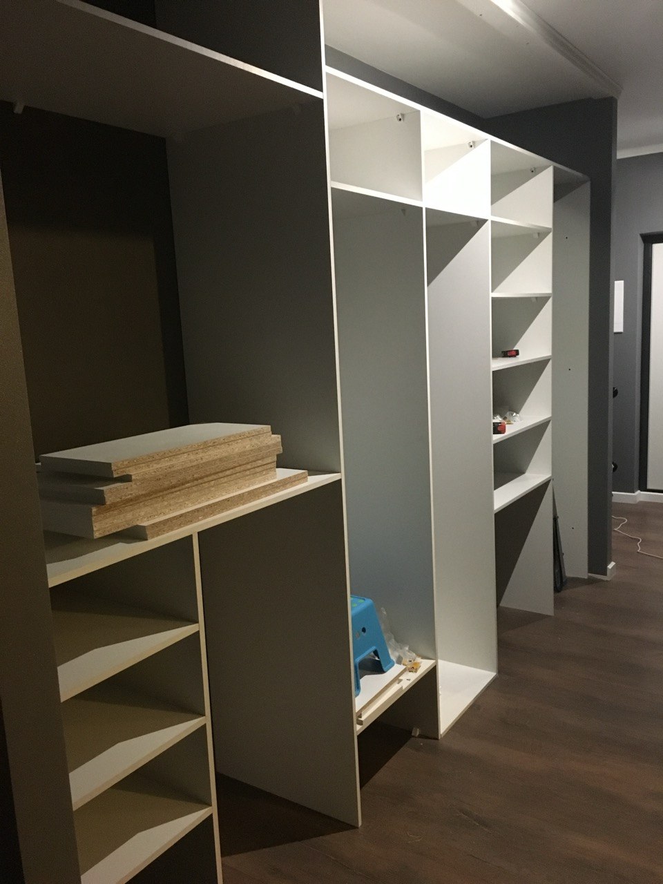 Large built-in wardrobe being assembled, multiple white shelf units in progress, Algarve